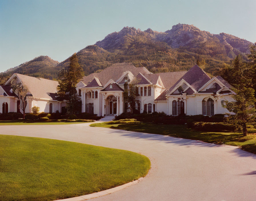 Luxurious suburban home with white facade and gabled roofs against mountain backdrop