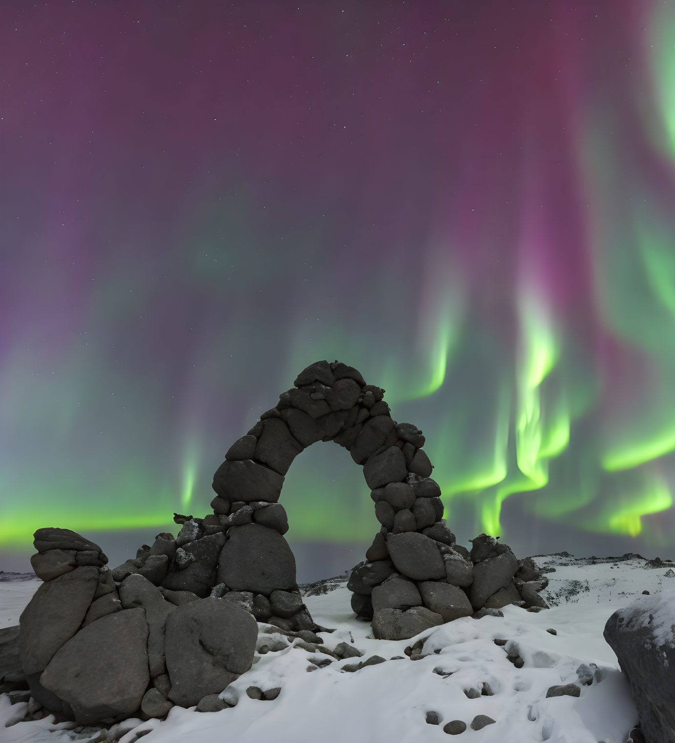 Stone Arch Framed by Northern Lights Over Snowy Landscape