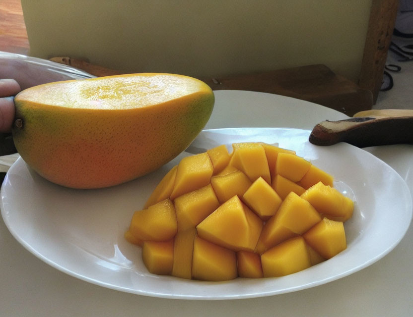 Fresh sliced mango on white plate with wooden table background