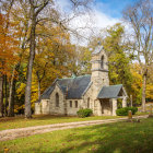 Church with steeple in autumn setting at sunset with winding path and fence.