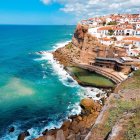 Scenic coastal cliffside town with boats and staircase by clear blue sea