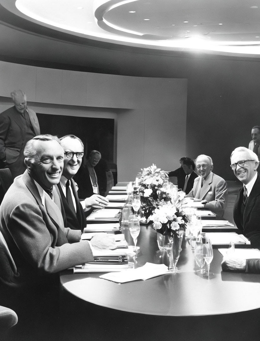 Group of Men in Suits Smiling at Oval Conference Table