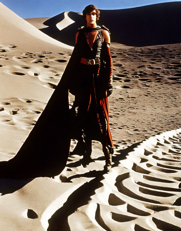 Person in Red and Black Outfit on Rippled Sand Dunes under Blue Sky