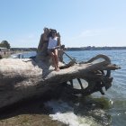 Shimmering blue tail mermaid sitting on rock by calm sea