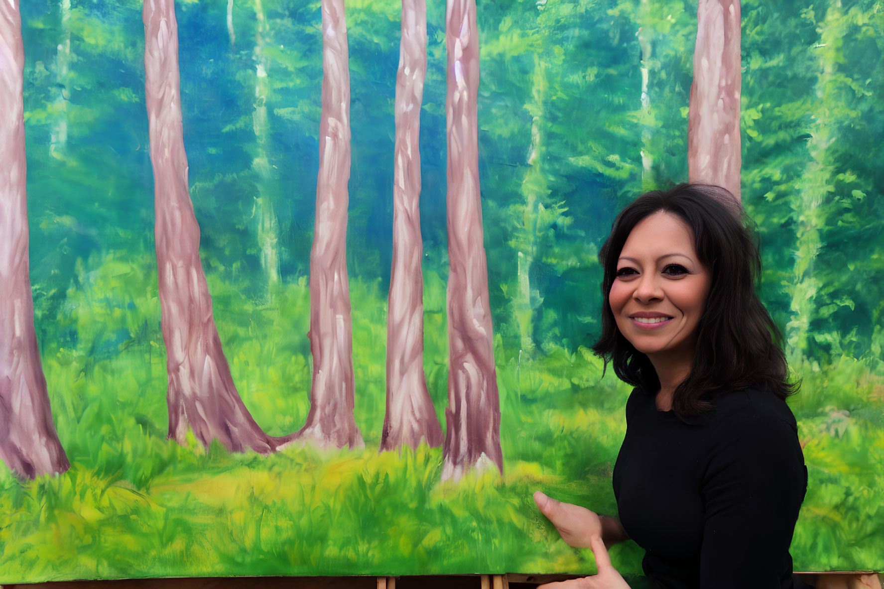 Dark-haired woman in black top smiles in front of vibrant green forest painting