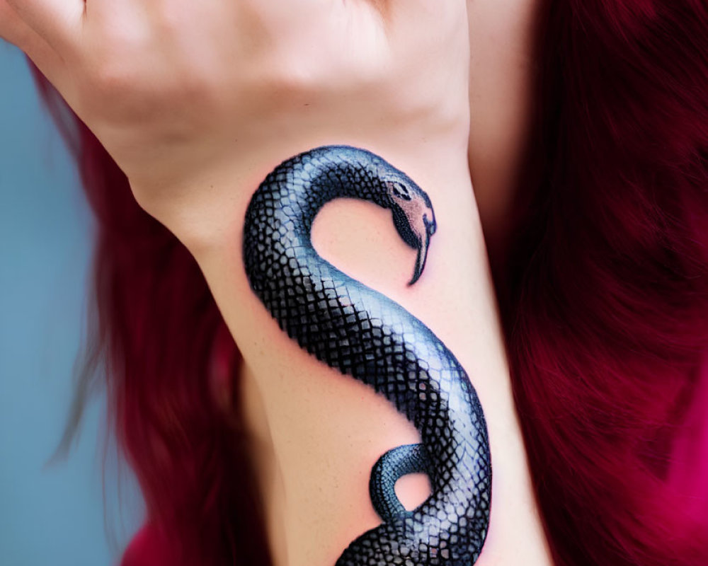 Red-haired person displaying realistic snake tattoo on forearm against blue background