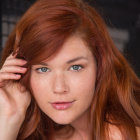 Red-haired woman in futuristic red and gold armor on dark background