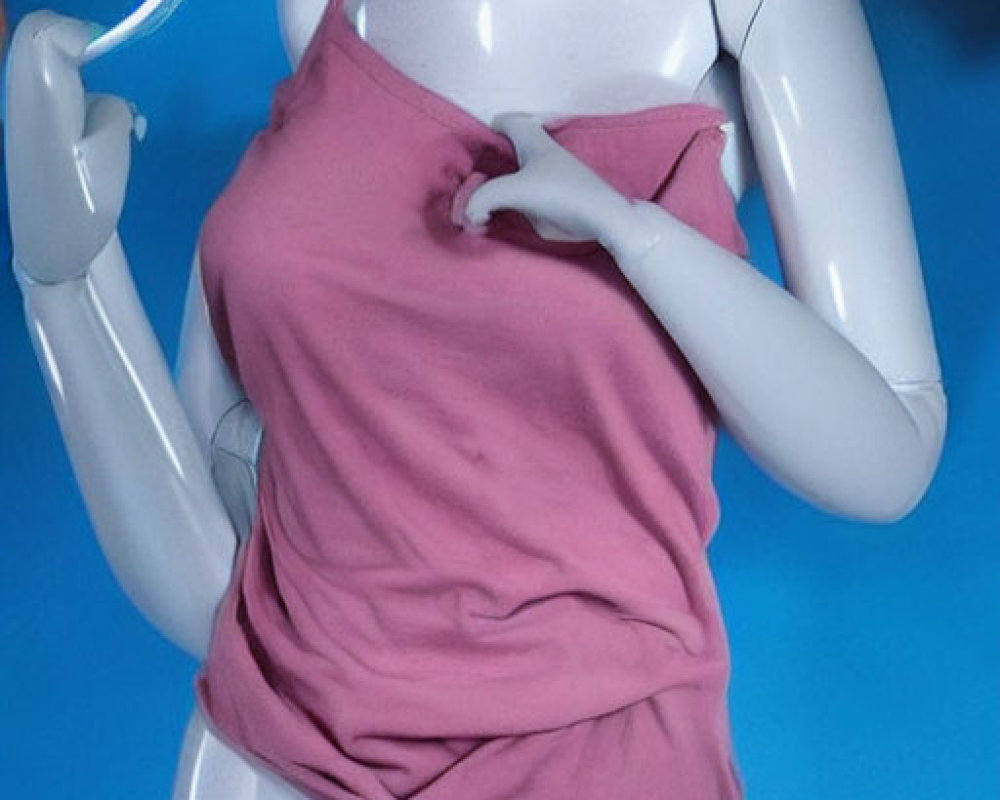 Blank-faced mannequin in pink tank top holding circular object on blue background