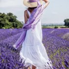 Colorful Woman in White Dress with Red Accents Holding Hat in Floral Landscape