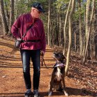 Man in leather jacket with large dog in autumn forest