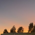 Orange Hued Dramatic Sky with Contrails Over Silhouetted Landscapes