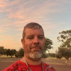 Regal man with beard in traditional attire on African savannah at sunset