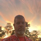 Elder with painted face and beads gazing at sunset in Australian Outback