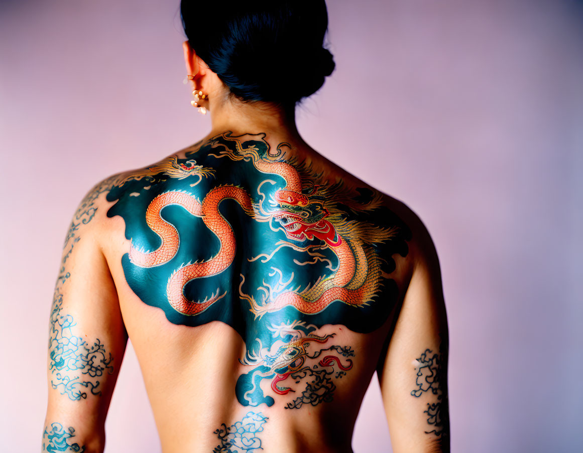 Intricate dragon tattoo on person's back against pink background