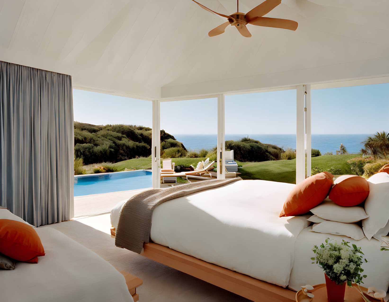 Spacious bedroom with ocean view, white decor, large windows, and green plant