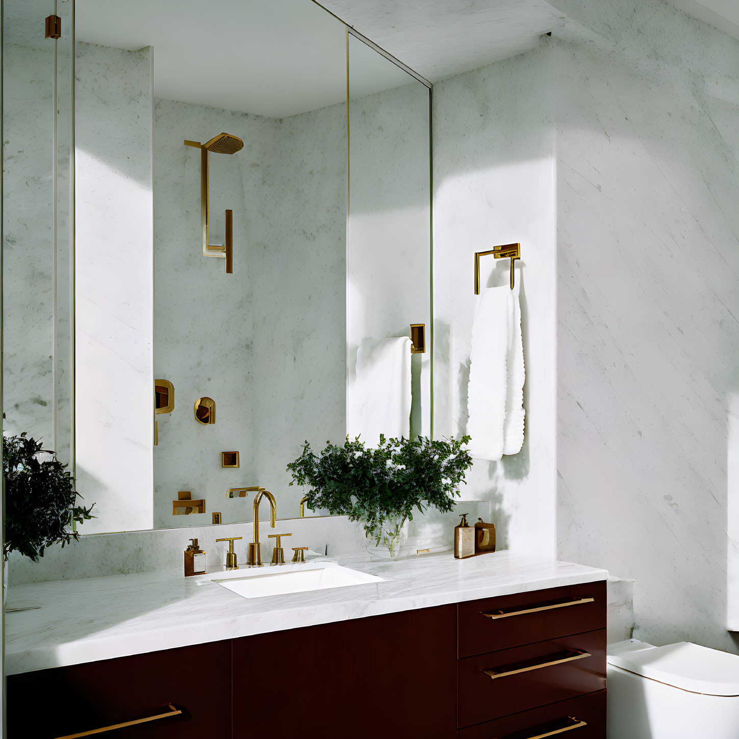 Stylish bathroom with marble walls, wooden vanity, white countertop, brass fixtures, and green