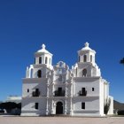 Historic white church with bell towers in watercolor art.