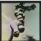 Monochrome photo of two models with avant-garde hats and accessories, umbrella, and surreal swirling sculpture