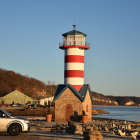 Colorful illustration of striped lighthouse, vintage car, buildings, and raindrops.