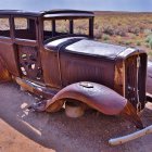 Rusty car with headlights in foggy forest clearing at sunrise or sunset