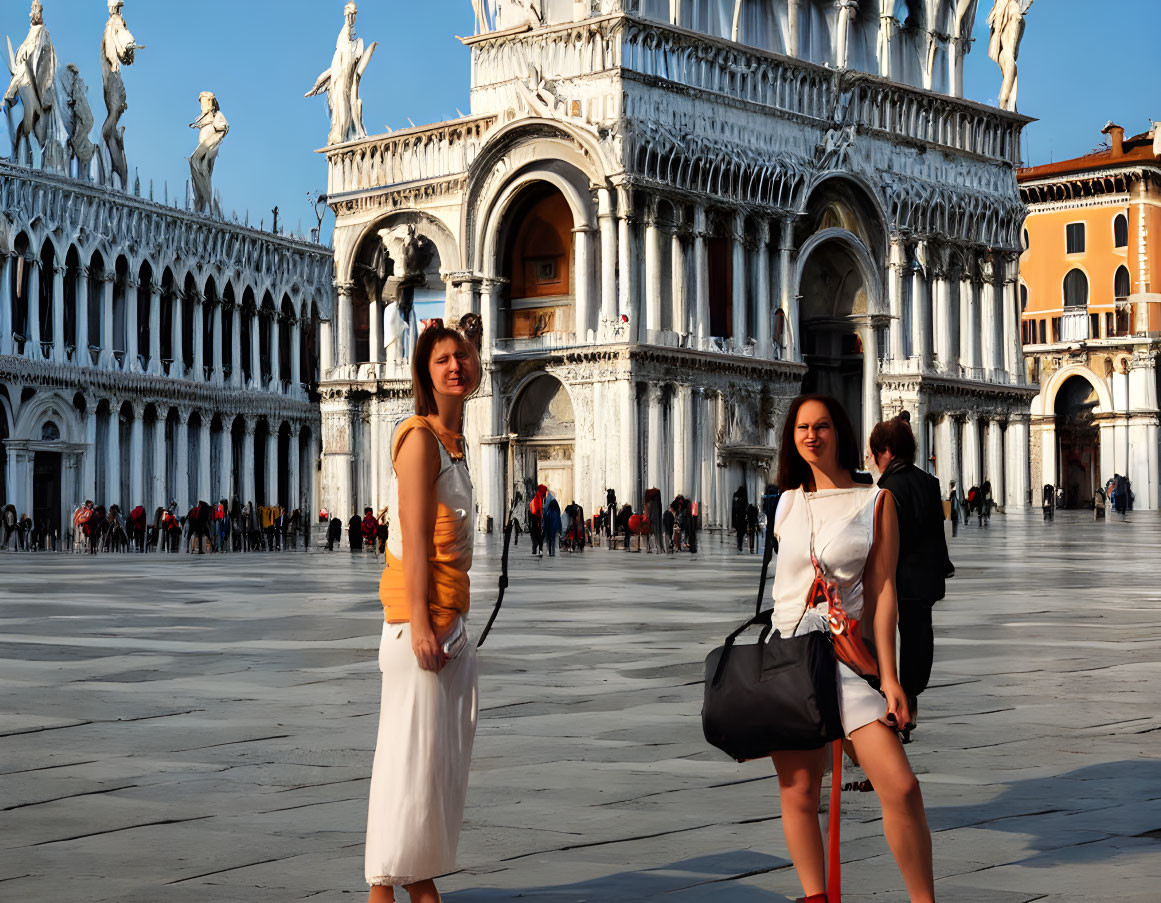 Women posing in sunlit square with historic buildings & statues.