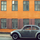 Vintage Beetle Car Parked Beside Orange Wall with Graffiti