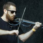 Bearded man playing violin with sunglasses on dark textured background