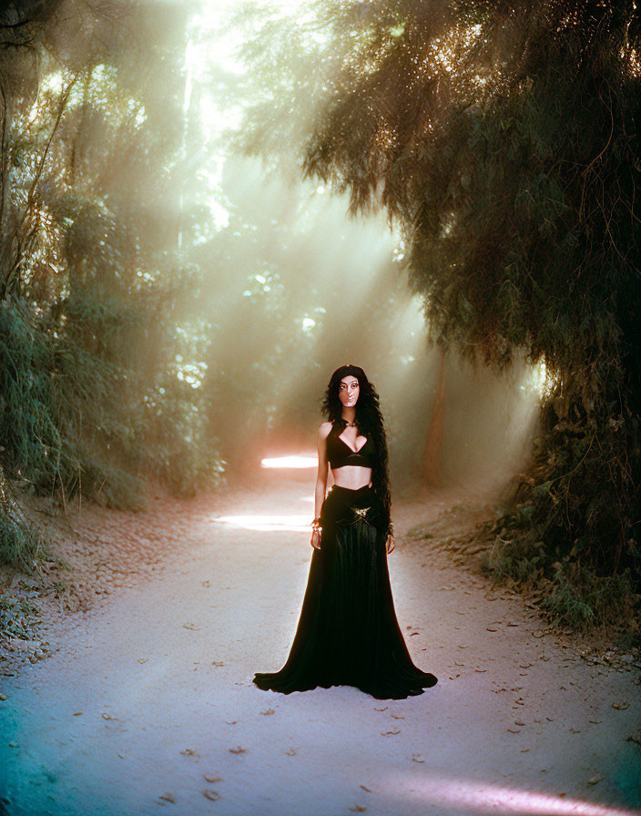 Woman in Black Dress Standing on Forest Path with Mystical Atmosphere