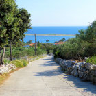 Tranquil coastal village scene with dusty road and Mediterranean-style houses