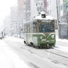 Vintage green tram in snowy cityscape with pedestrian, streetlights, and buildings.