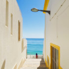 White-walled alleyway to calm sea with lone figure