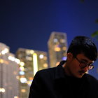 Pensive person in glasses against city night lights