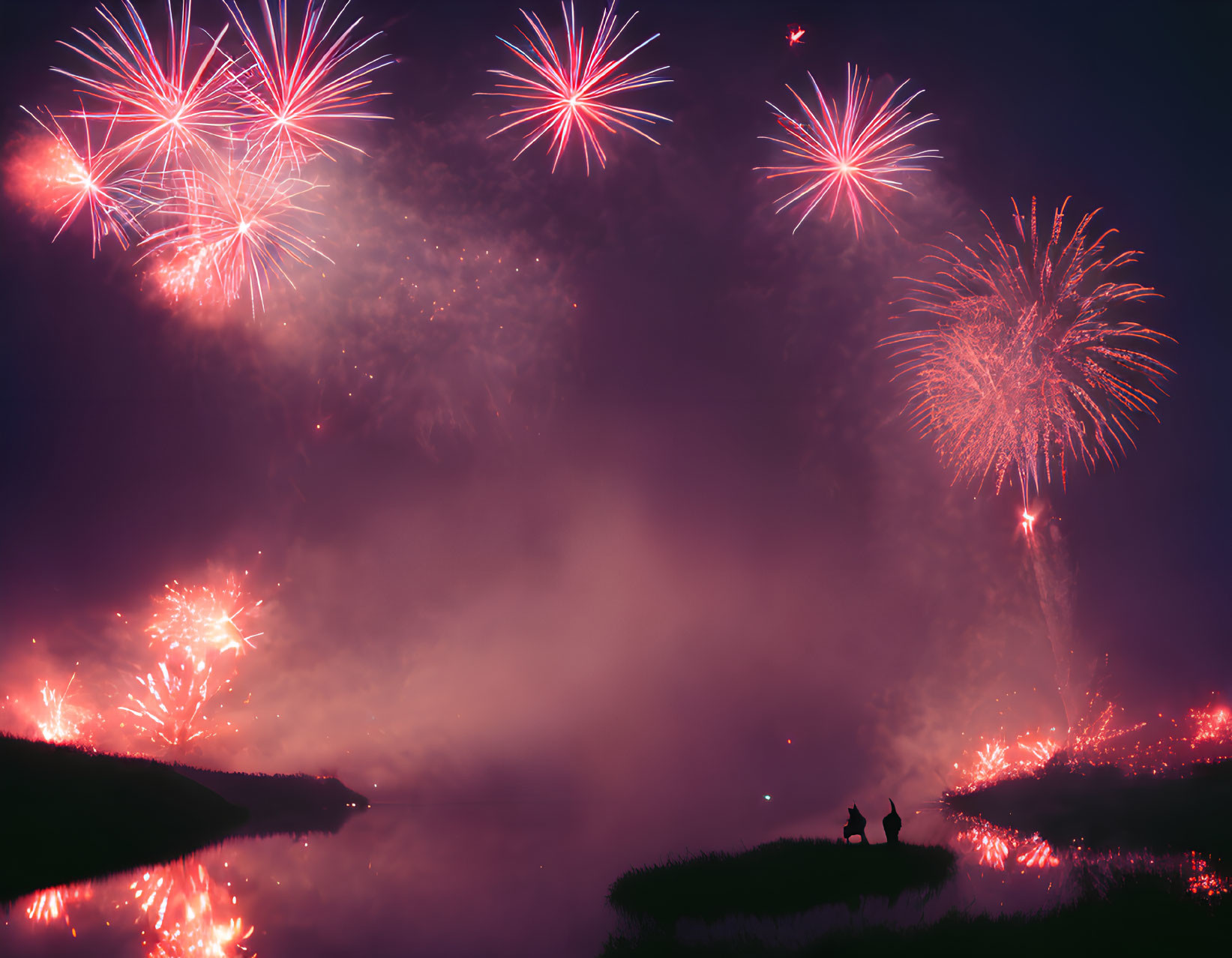 Silhouette of two people watching fireworks over lake