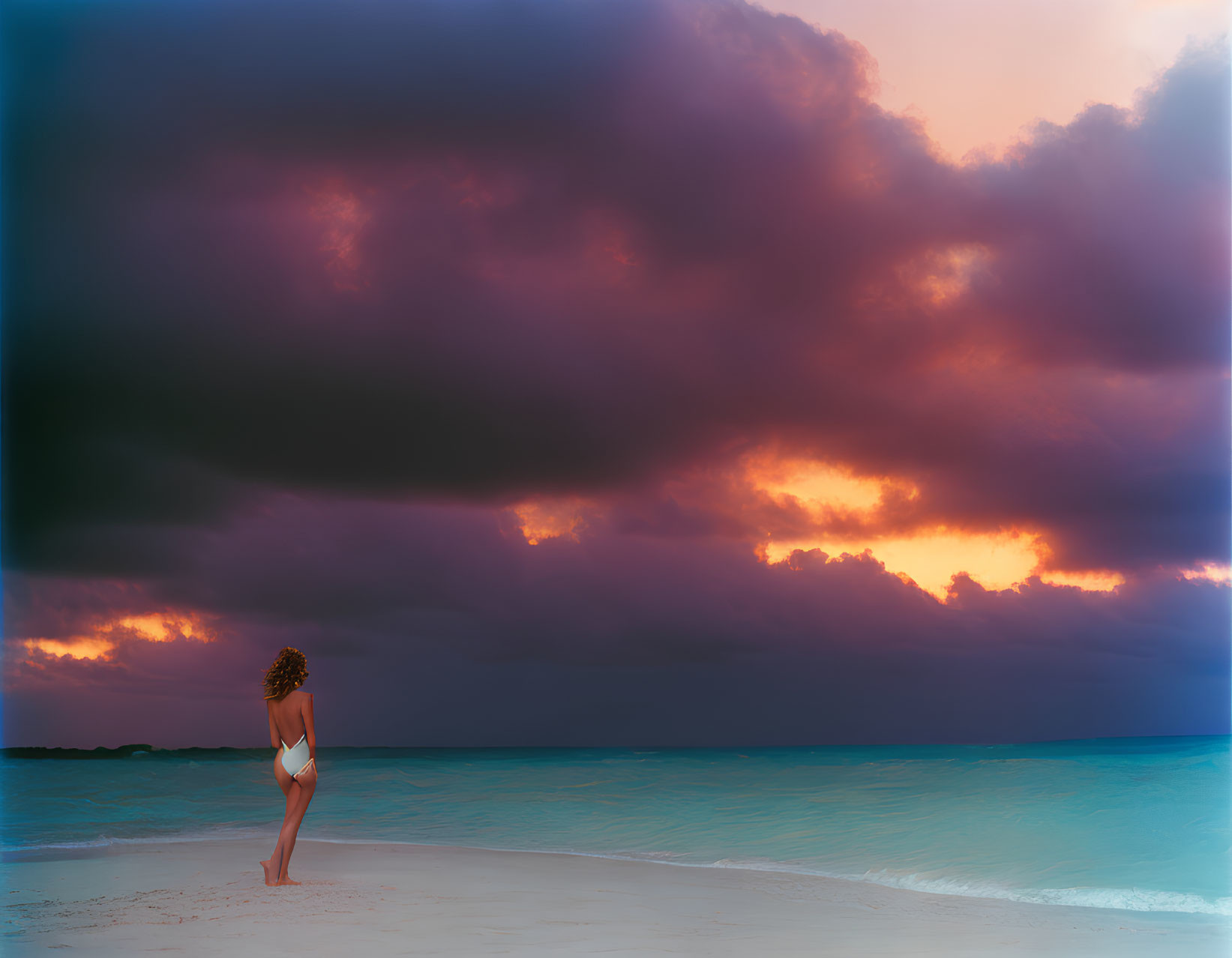 Person gazes at dramatic sky over beach at sunrise or sunset