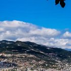 Panoramic view: Sheep grazing on hilly terrain under dramatic sky