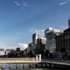 Cityscape with dark tones contrasted by sunlit beach, soaring birds, skyscrapers, and