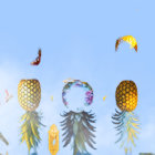 Stylized pineapples as bird, woman, and leaf figures against blue sky