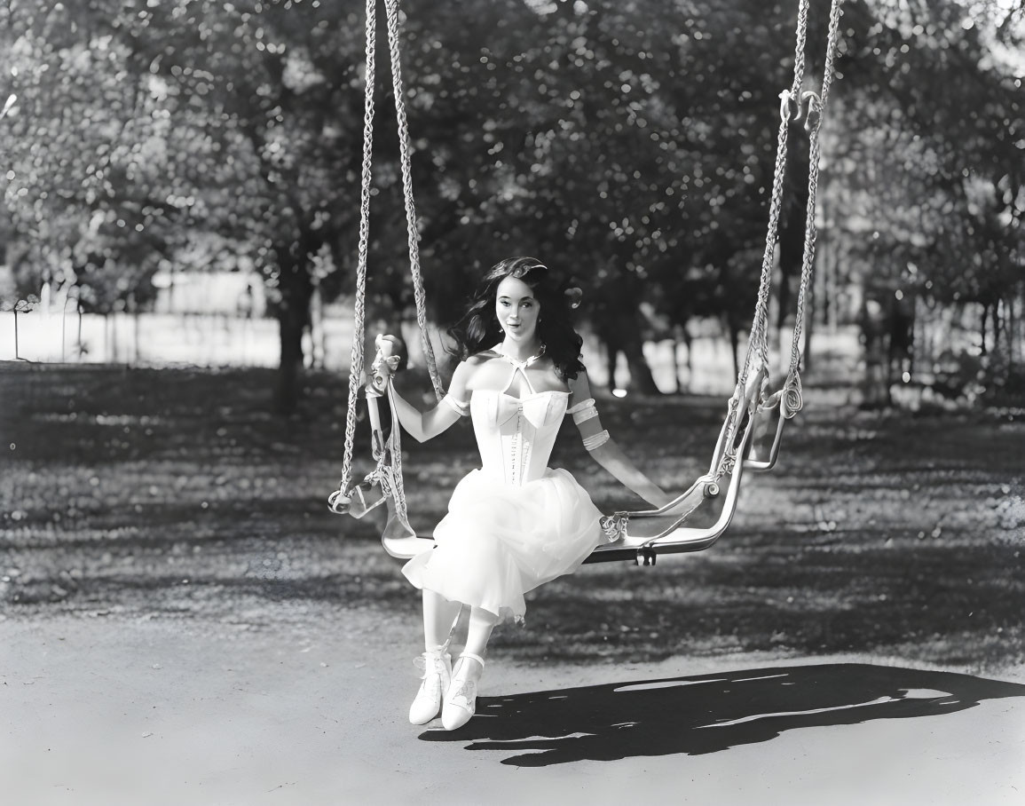 Vintage-dressed woman on swing in park, black and white photo