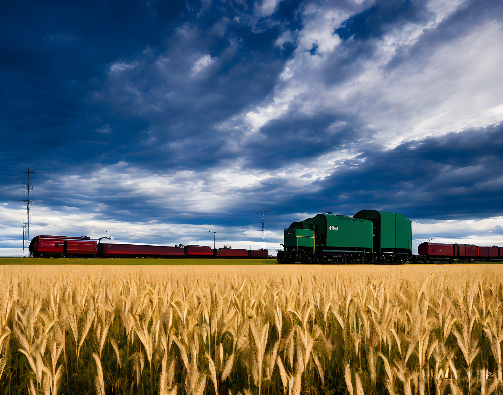 Green locomotive freight train crossing golden wheat fields under dramatic sky