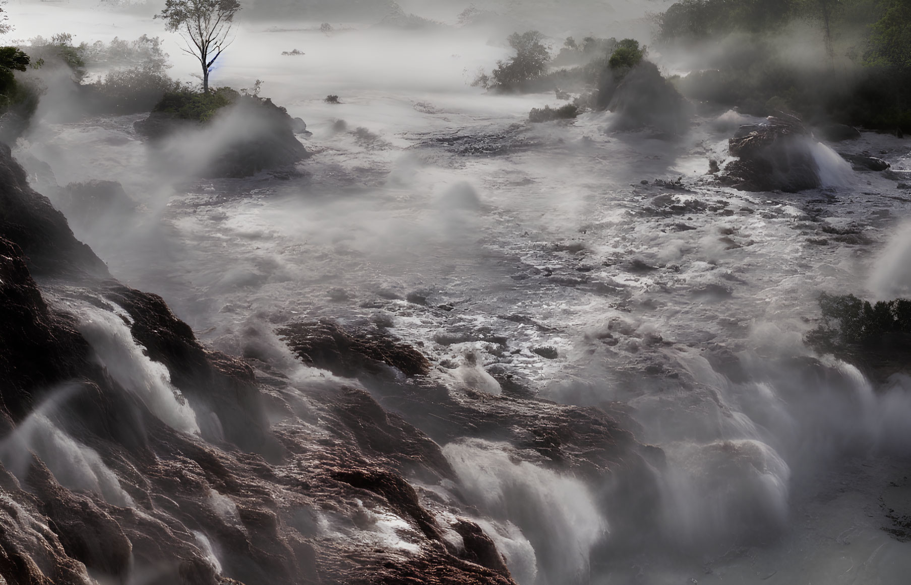 Scenic misty waterfall with tree in foggy landscape