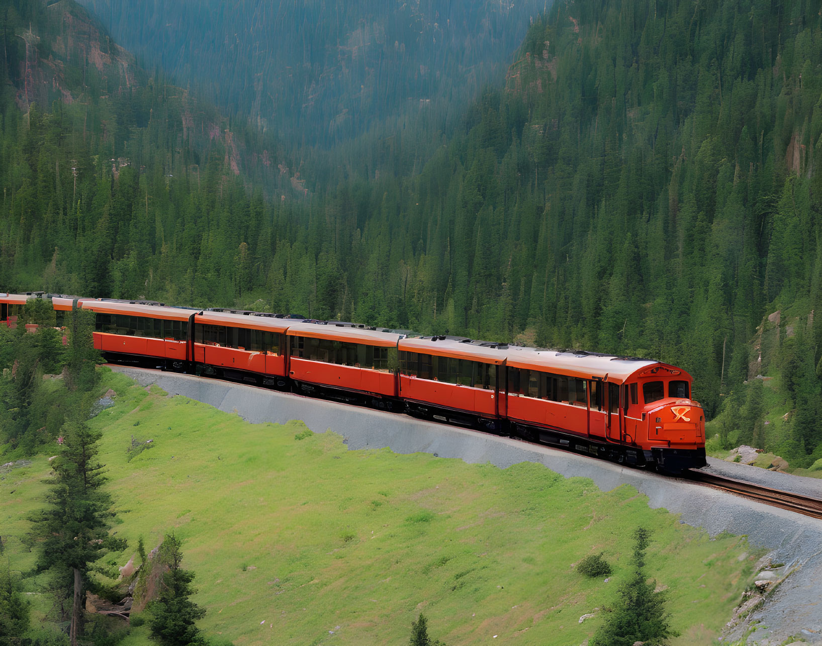 Red Train Snaking Through Lush Green Mountainous Landscape