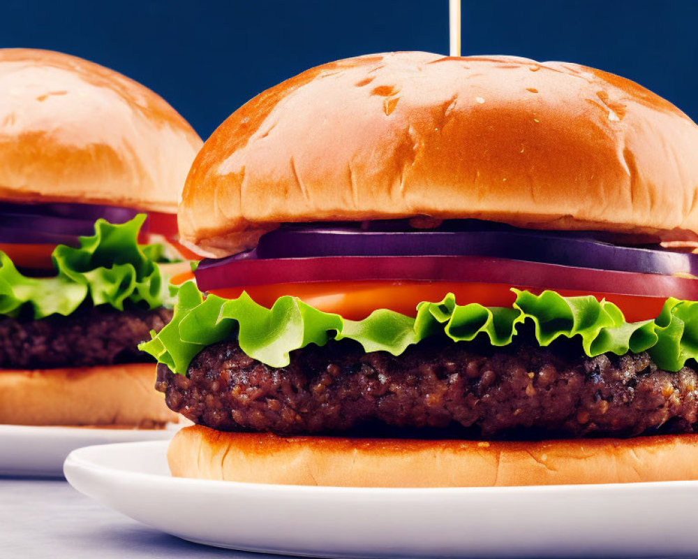 Two cheeseburgers on brioche buns with lettuce, tomatoes, onions on white plates