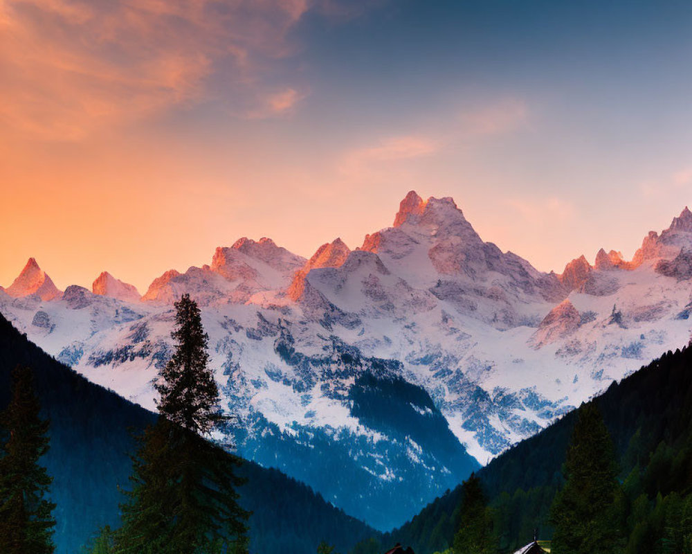 Snow-capped mountains at sunset with blue sky above and serene valley below.