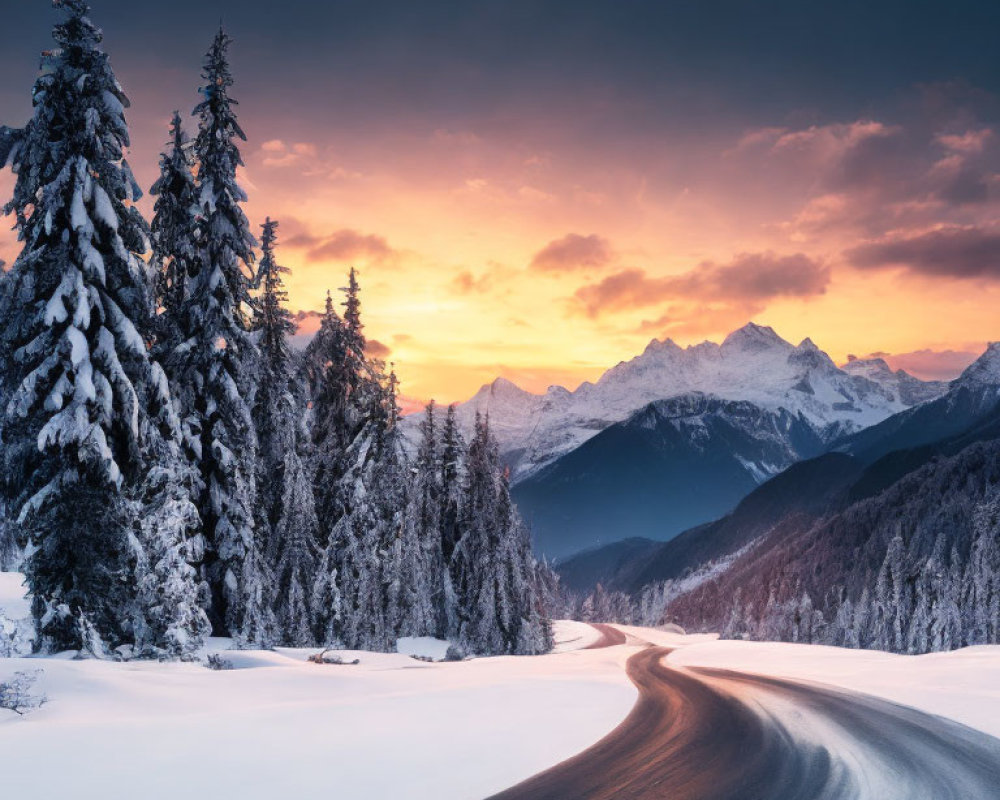 Snow-covered landscape with winding road and sunset over mountain peaks