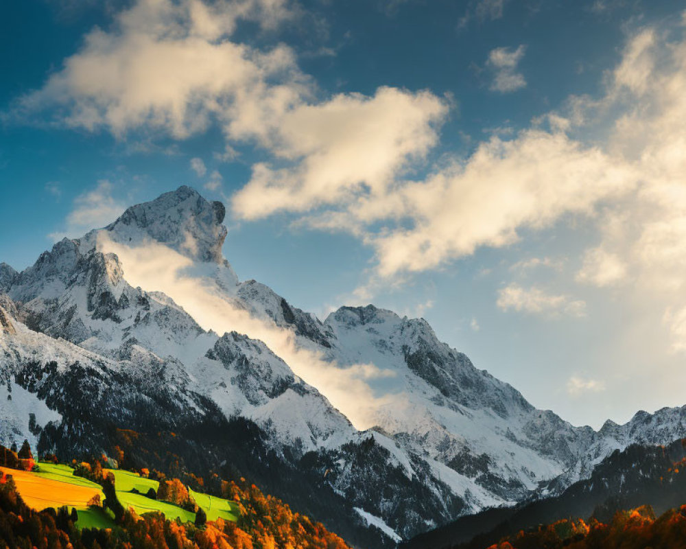 Snow-capped mountain peaks above vibrant autumn foliage under a dramatic sky