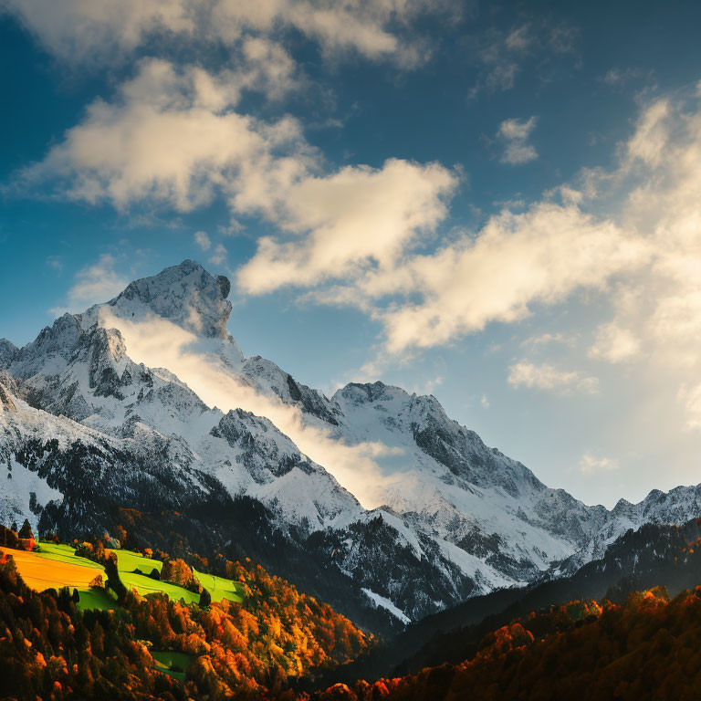 Snow-capped mountain peaks above vibrant autumn foliage under a dramatic sky