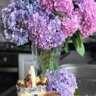 Purple hydrangeas in a vase with tea set on table in watercolor art