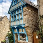 Three-Story Stone House with Blue Shutters in Greenery