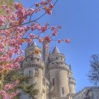 Vibrant fairytale castle with blue roofs amid pink cherry blossoms