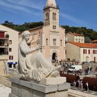 Whimsical hillside town by the sea with bell tower & colorful buildings